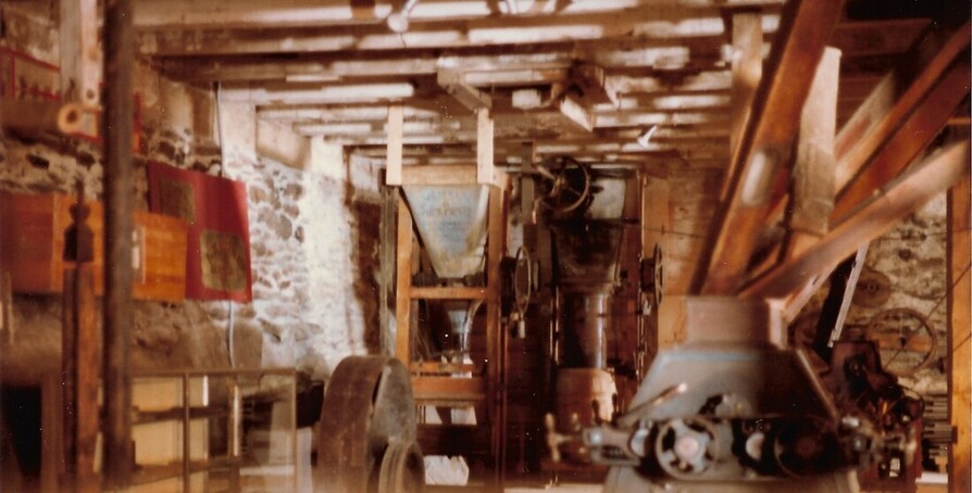 Picture: 27 – The museum that the society created in the mill basement in 1981 as seen on March 13, 1983. Although a poor photo, one can see the flour packers in the center distance, one of the line of roller mills on the right, and on the left a display of the silks from the Wolf Level Sifter that the society had acquired from the Pleasant Valley Roller Mills. These sorted the grist from the roller mills into different categories, sending some to another roller mill, some to the flour bin, and some to the bran duster.